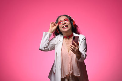 Portrait of young woman standing against yellow background
