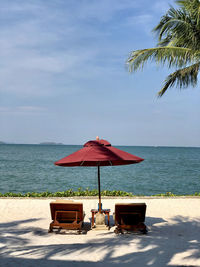 Chairs on beach by sea against sky