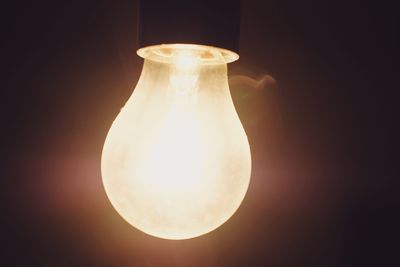 Close-up of illuminated light bulb against black background