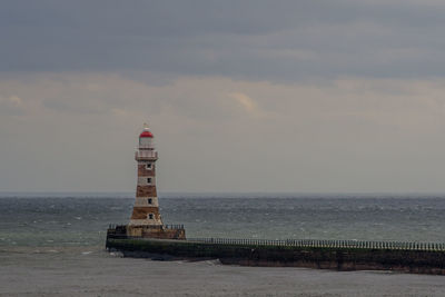 Lighthouse by sea against sky