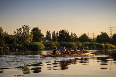 People in lake against clear sky