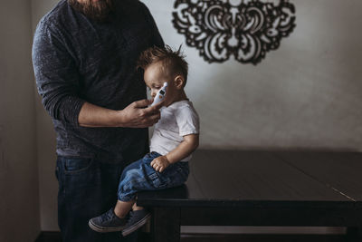 Midrange view of father taking young sons temperature at home