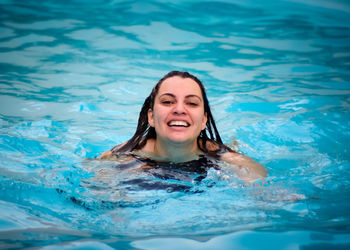 Portrait of a smiling young woman swimming in pool