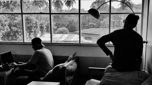 Rear view of woman sitting on table at home