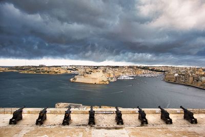High angle view of cannons against cloudy sky with view on the three cities in malta