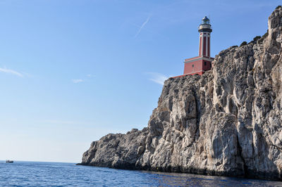 Lighthouse by sea against sky