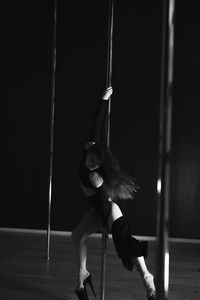 Low angle view of young woman standing against black background