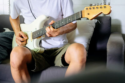 Midsection of man playing guitar