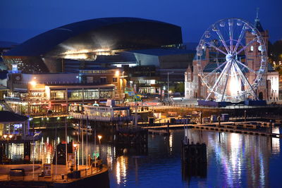 Illuminated ferris wheel in city at night