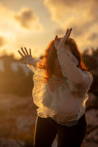 Rear view of woman standing in water during sunset