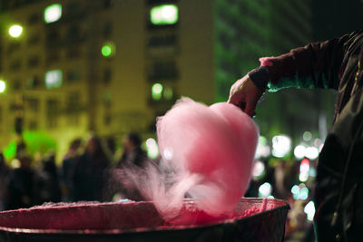 Cropped hand of man preparing pink cotton candy