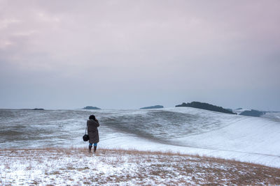 Rear view of man walking on a field during winter