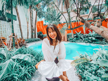 Portrait of smiling young woman standing against plants