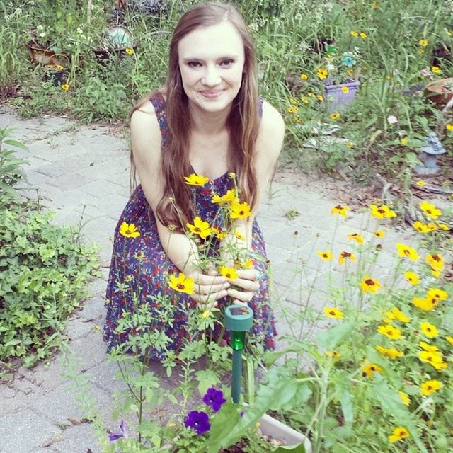 flower, person, casual clothing, lifestyles, leisure activity, looking at camera, portrait, standing, smiling, young adult, plant, front view, young women, growth, high angle view, freshness, full length, three quarter length