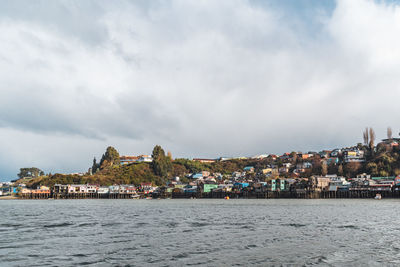 Buildings by sea against sky