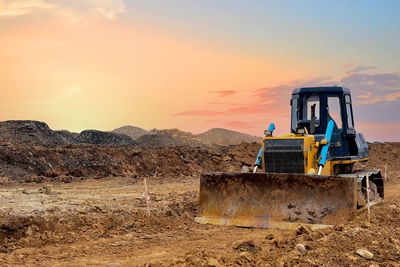 Construction site on field against sky during sunset