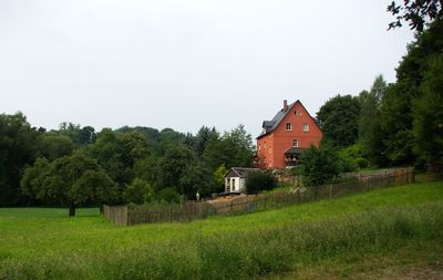 Trees and houses on field against sky