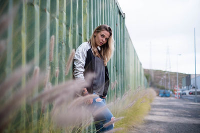 Portrait of young woman standing by cargo container