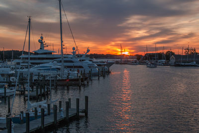 Sailboats moored at harbor during sunset