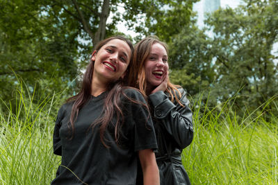 Portrait of cheerful friends standing on field