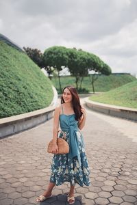 Full length of woman standing in park against sky