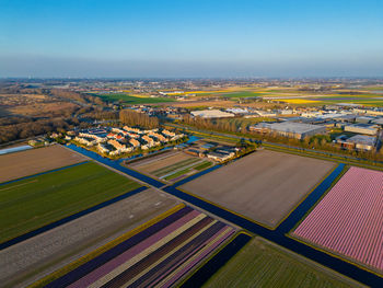 Aerial view of a peaceful suburban neighborhood surrounded by fields and canals. neat rows of houses