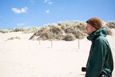 Rear view of man standing at beach against sky