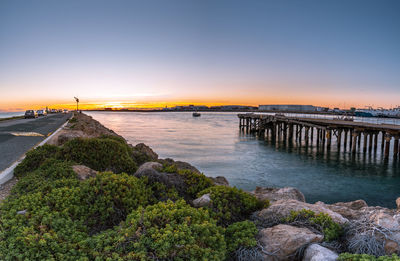 Bridge over sea against sky during sunset