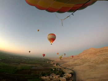 Hot air balloons flying over landscape against sky