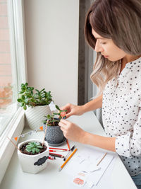 Woman looking at potted plant on table