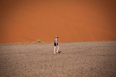 Full length of woman walking in desert on sunny day