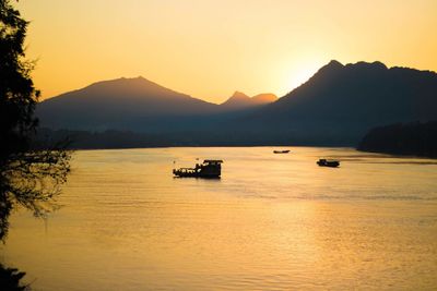 Silhouette boat in sea against sky during sunset