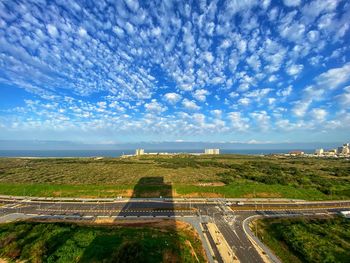 Road amidst green landscape against blue sky