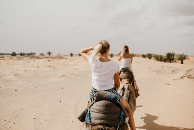 Rear view of women riding camels at desert