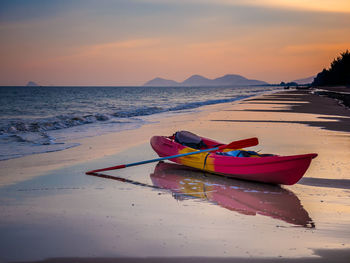 Boat moored on beach against sky during sunset