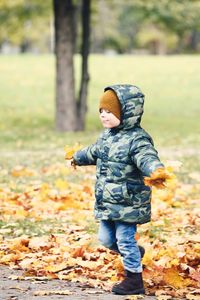 Rear view of boy playing on field during autumn