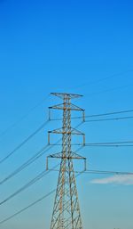 Low angle view of electricity pylon against clear blue sky