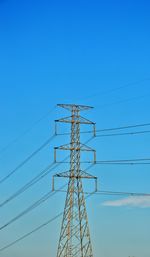 Low angle view of electricity pylon against clear blue sky