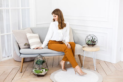 Young woman sitting on sofa at home