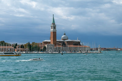 View of buildings at waterfront against cloudy sky