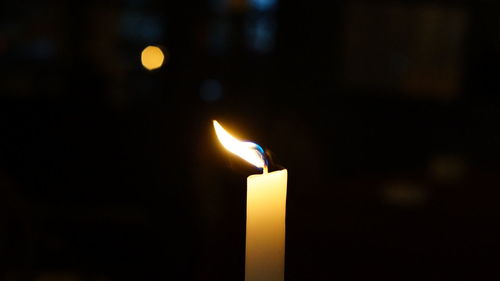 Close-up of lit candle at night