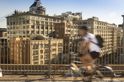 Blurred motion of man riding bicycle on building in city