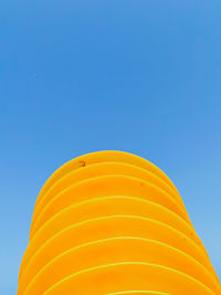 Very colourful chairs in a pile with blue sky in the background