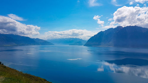 Scenic view of sea and mountains against blue sky