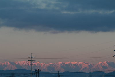 Scenic view of mountain range against cloudy sky during sunrise