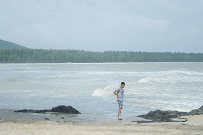 Full length of man standing on beach against sky