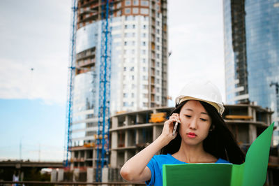 Female architect standing against incomplete building