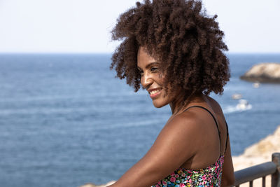 Portrait of smiling young woman against sea