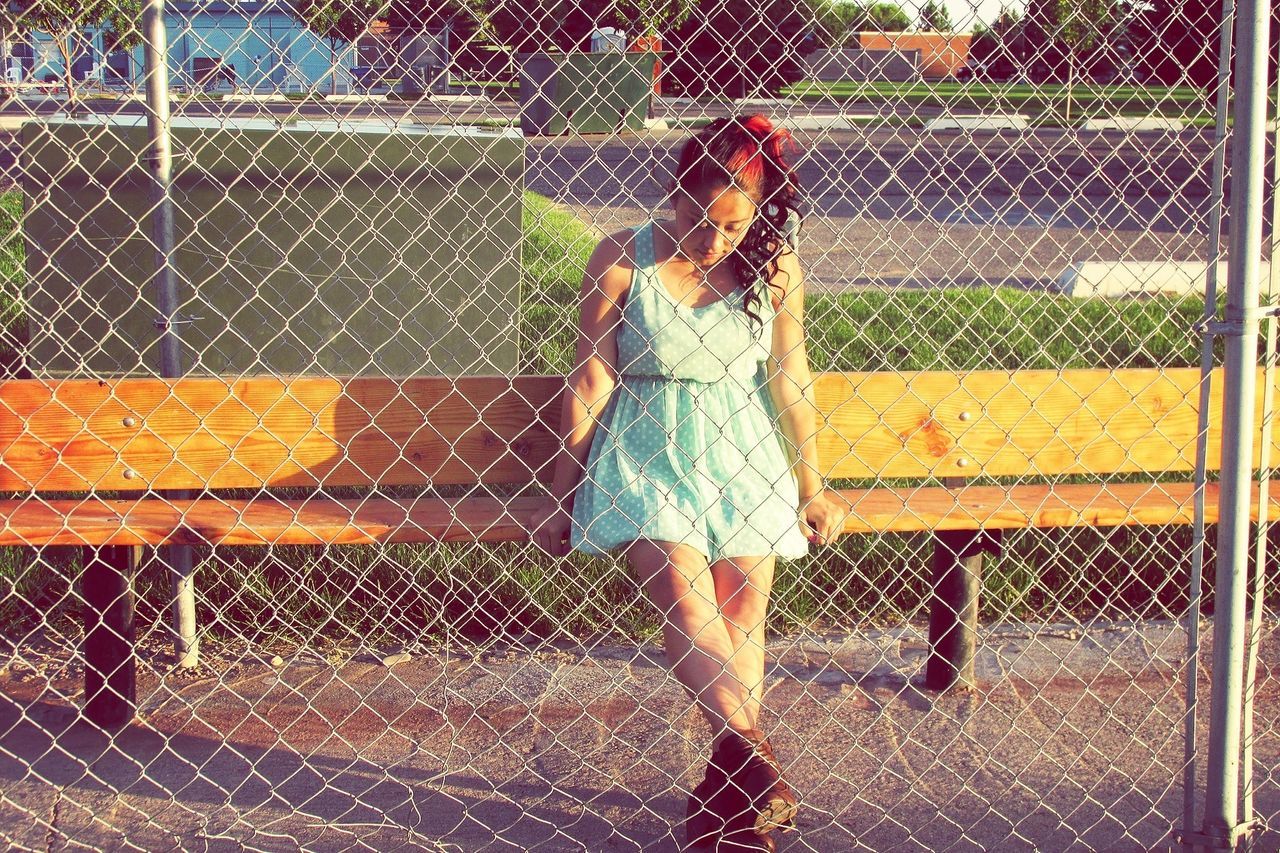 lifestyles, leisure activity, fence, protection, standing, chainlink fence, casual clothing, person, safety, full length, metal, day, street, wet, outdoors, railing, walking, sidewalk