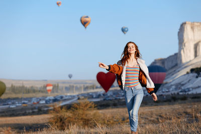 Rear view of woman with balloons on field